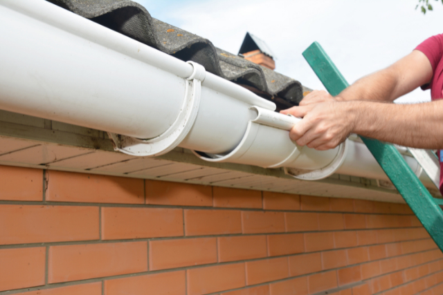 Gutter Repair by worker standing on a ladder