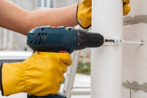 Installation of gutter system by worker with drill