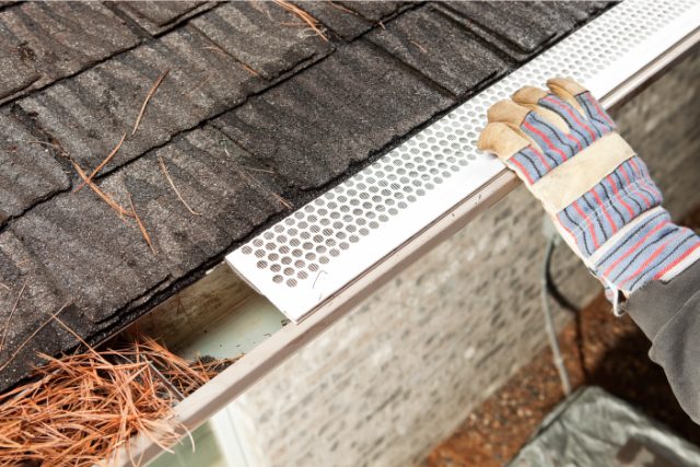 Gutter guard installation Gutter guard installation by a worker with gloves on